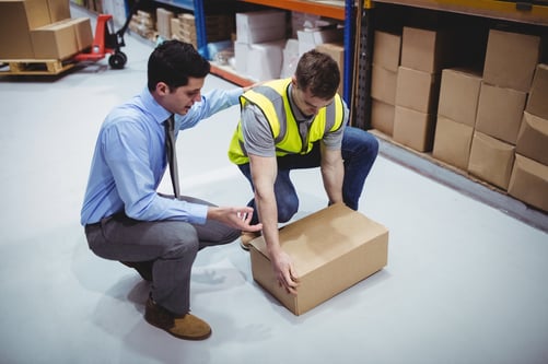 leader helping worker pick up box